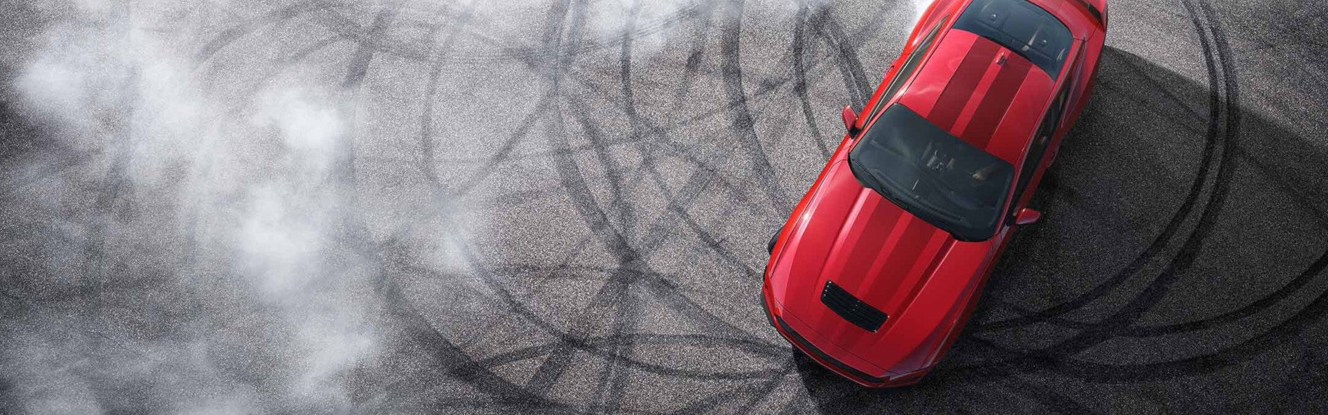 Red 2024 Ford Mustang doing donunts on pavement