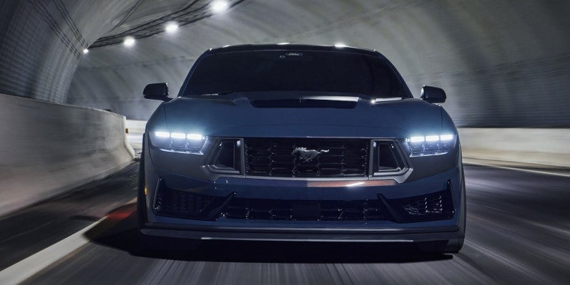 Blue 2024 Ford Mustang driving on road in tunnel