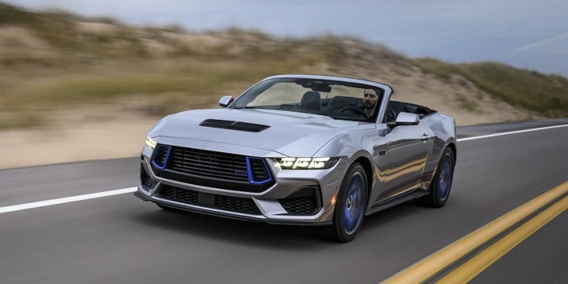 Gray 2024 Ford Mustang driving on whighway with desert in background